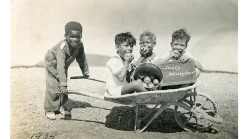 Oorspronkelijk bijschrift: "Nieuwjaarswens. Vier jongetjes met een kruiwagen," Curaçao 1934. (Bron: Collectie Fraters van Tilburg / Stadsmuseum Tilburg inv. nr. 408511)